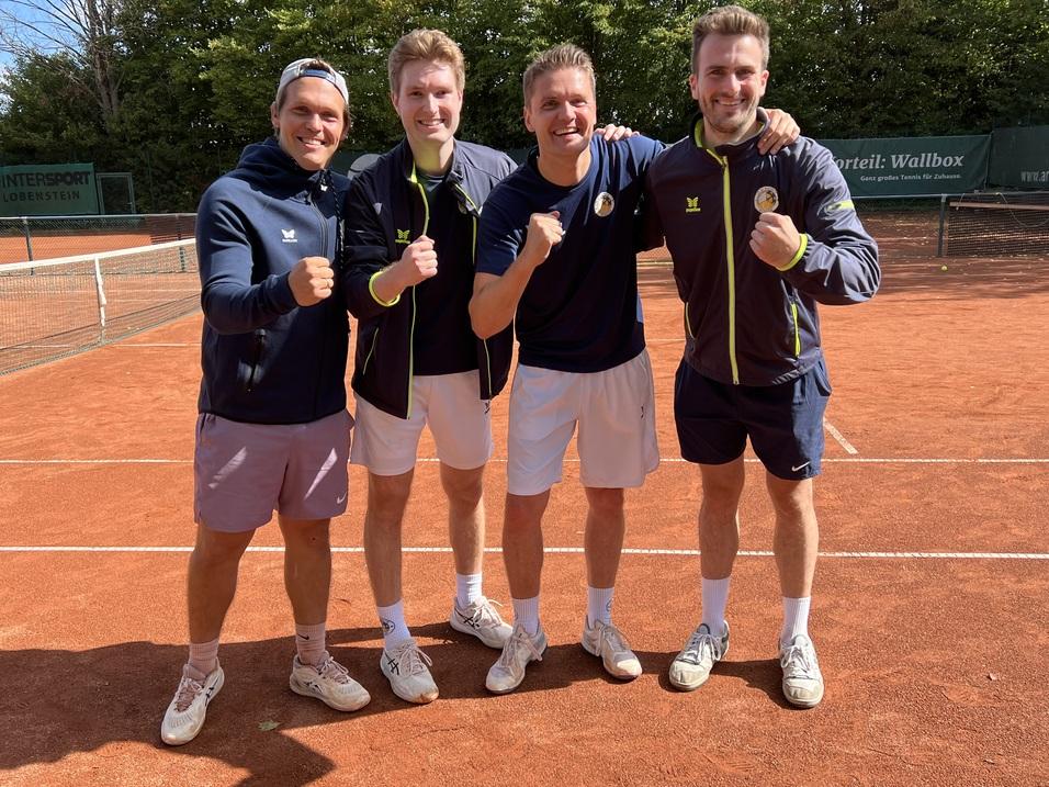 Vier Tennis-Spieler posieren lächelnd auf einem Tennisplatz aus rotem Sand und zeigen ihre Fäuste zur Freude.