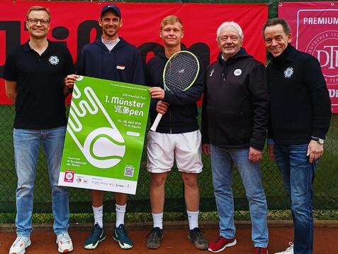 Fünf Personen stehen auf einem Tennisplatz mit einem Plakat für das 1. Münster Open in der Hand.